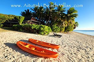 two red sea-kayaks on the beach beside Aitutaki Lagoon